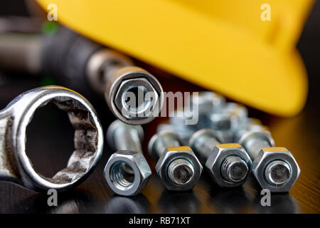 Screws, nuts and keys on a workshop table. Tools and accessories for mechanics. Black background. Stock Photo