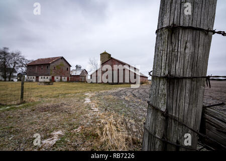 Fence post and barbed wire at the entrance to a rural midwest farm on a cold winters day. Plano, Illinois. Stock Photo