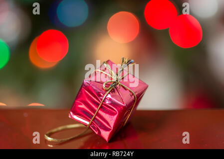 Gift box wrapped in gold wrapping paper, decorated with red raffia ribbon  and bow isolated on the white background Stock Photo - Alamy