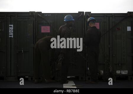 Combat cargo Marines lash containers to the deck of USS Carter Hall (LSD-50) Dec. 1, 2016 during Amphibious Ready Group, 24th Marine Expeditionary Unit Exercise off the coast of Onslow Beach, North Carolina. These Marines were assigned the combat cargo billet as a part of ship taxes and come from a myriad of military occupational specialties native to the Marine units aboard Carter Hall. They play a key role in the on and offloading of vehicles and equipment on amphibious vessels, working long hours to accomplish their mission. Stock Photo