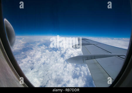 View from the window of the plane onto the wing and engines of a fokker 100 model with a blue sky and white clouds. Sunny weather Stock Photo