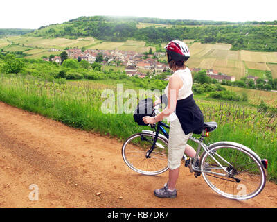 Woman wearing cycle helmet  stopped to look at the view on a bike cycle ride in the French countryside near Meursault in the Burgundy region of France Stock Photo