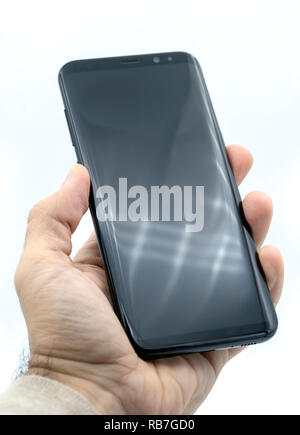 Hand holding Samsung Galaxy S8 Plus smart phone cut out on a white background Stock Photo