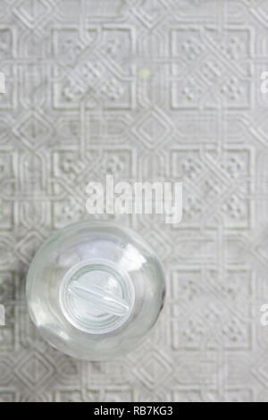 Overhead view of glass vial on pressed tin with specular highlights and soft focus background Stock Photo