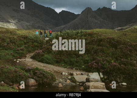 Tourits exploring the Fairy Pools on the Isle of Skye, in front of the Cuillin mountain range, UK Stock Photo
