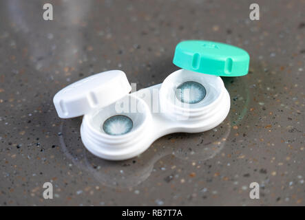 Container with green contact lenses on white background Stock Photo