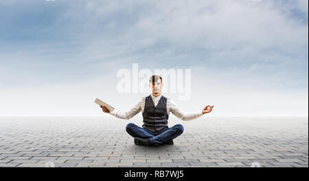 Businessman in lotus pose. Mixed media Stock Photo