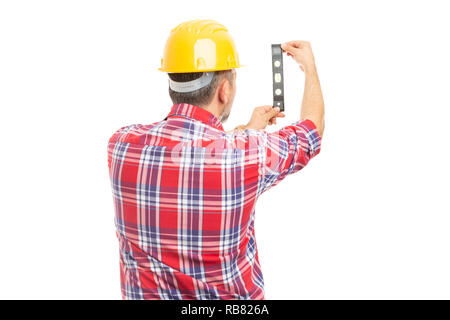 Builder man with back to camera checking vertical surface with bubble level isolated on white background Stock Photo