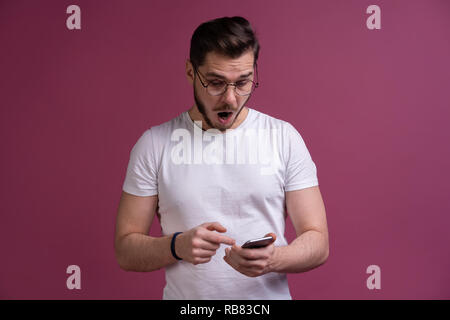 You will have problems man! Portrait of angry confused aggressive in bad mood guy shouting threatening in the loud-speaker of his smartphone, isolated on pink background. Stock Photo