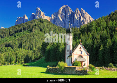 The church St. Johann in Ranui in the Villnoess / Funes valley in the Dolomites, South Tyrol, Italy. In the background the Geisler Group mountain rang Stock Photo