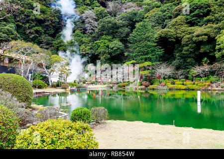 The pond and garden with green water and reflection of tree in the water located at Umi Jigoku or sea hell featuring a pond with blue hot stream water Stock Photo