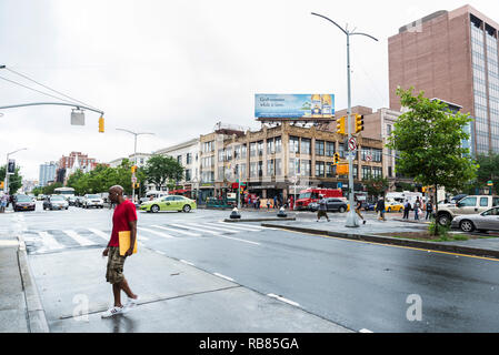 New York City, USA - July 25, 2018: Traffic on Malcolm X Boulevard with people around in Harlem, Manhattan, New York City, USA Stock Photo