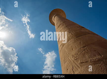 Columns with hieroglyphic carvings in hypostyle hall at anciant egyptian Karnak Temple in Luxor against blue sky background Stock Photo