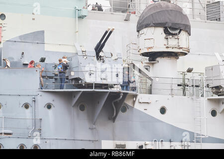 Two families look at guns of the warship HMS Belfast, a world war II cruiser ship now anchored on the river Thames in the city of London near Tower Br Stock Photo