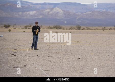 U.S. Air Force 1st Lt. Tyler Wallis, from Robins Air Force Base, Ga., measures out a distance in preparation for his team setting up their equipment for the 2016 Air Force Research Laboratory Commanders Challenge at the Nevada National Security Site, Las Vegas, NV., Dec. 9, 2016. This year teams were given the challenge of solving issues revolving around drones, and are demonstrating their solutions to judges. Stock Photo