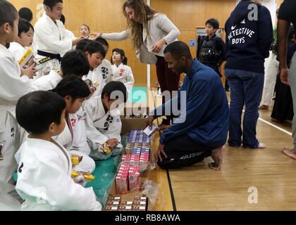 CAMP KENGUN, Kumamoto City, Kumamoto Prefecture, Japan – Sgt. Quincy Williams, military police noncommissioned officer-in-charge with the 247th MP Detachment and Sgt. Linda Burkett, transportation specialist with the 35th Combat Sustainment Support Battalion, hand out cookies and drinks to the children of the Kumamoto City police station Kendo dojo.  The Soldiers attended Kendo training at the Kumamoto city police station to foster good relations between the U.S. military and the Japanese people during Yama Sakura 71. Exercise Yama Sakura 71 is an annual command post exercise co-sponsored by U Stock Photo