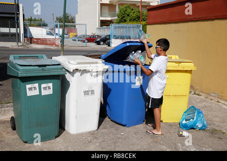 11-year-old boy throwing garbage into recycling bins in Salento, Italy. Stock Photo