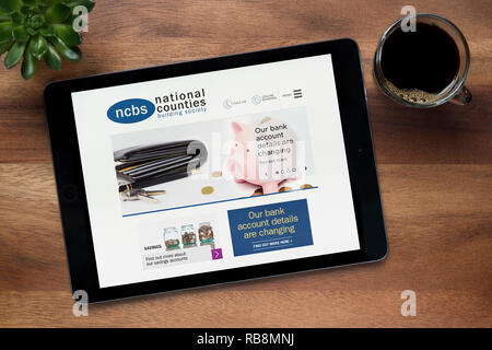 The website of National Counties Building Society is seen on an iPad tablet resting on a wooden table (Editorial use only). Stock Photo