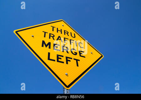 The 'Thru Traffic Merge Left' street sign in the Californian sun. Stock Photo