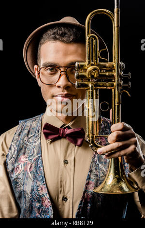 portrait of stylish young male musician posing with trumpet isolated on black Stock Photo
