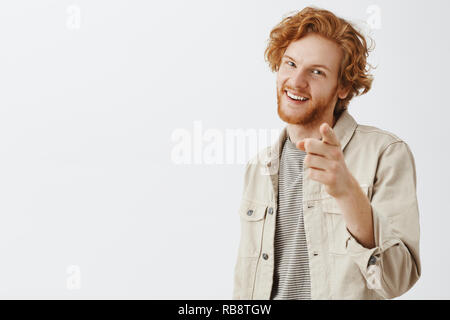 You old fox. Portrait of pleased enthusiastic handsome redhead male with beard and wavy hairstyle pointing at camera and smiling joyfully as if congratulating friend or hinting at something Stock Photo