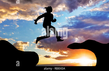 Woman jump over canyon at a sunset Stock Photo