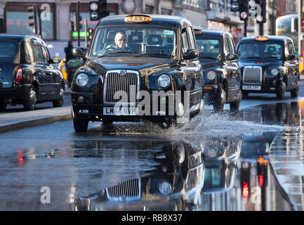 Taxis drive through standing water on Oxford Street, London, following a burst water main in one of the capital's busiest shopping streets. Stock Photo