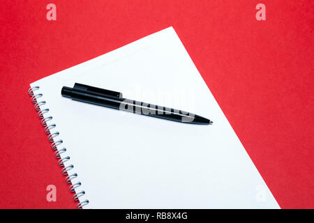Spring notebook and black pen on blank sheets white paper on red background. Concept of free space, copyspace, business book, notepad, diary, use for  Stock Photo