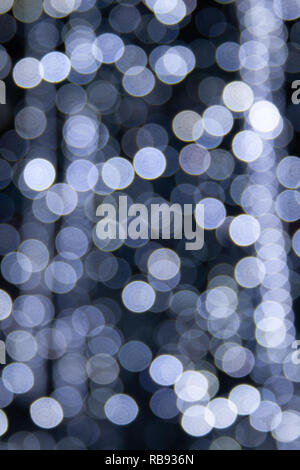 Abstract background white and grey bokeh lights, frozen fountain in winter, cascade of sparks, cold feeling, coldness, vertical image Stock Photo