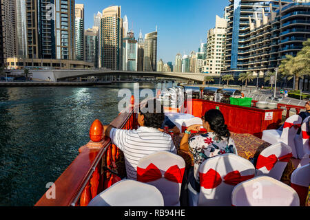 Dubai, UAE 11. 10. 2018 : Famous traditional wooden old dhow cruise tour in the marina with tourist on the board and modern skyscrapers in the backgou Stock Photo