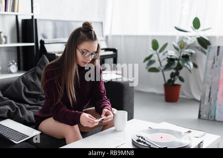 girl sitting at table and rolling marijuana joint in living room Stock Photo