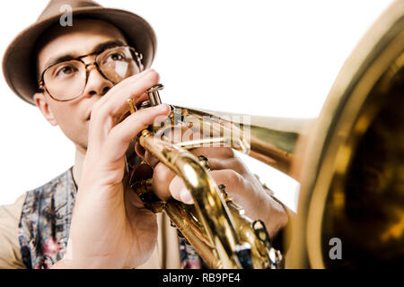 selective focus of mixed race male musician in stylish hat and eyeglasses playing on trumpet isolated on white Stock Photo