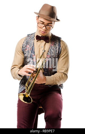 young male jazzman holding trumpet and sitting on chair isolated on white Stock Photo