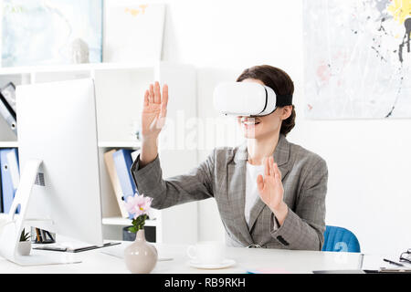 smiling businesswoman using virtual reality headset in office Stock Photo