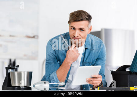 unhappy man holding screwdriver and digital tablet Stock Photo