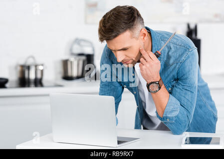 handsome man holding screwdriver and using laptop Stock Photo