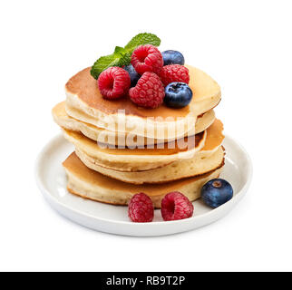 Stack of delicious pancakes with berries and mint leaf on plate isolated on white. Stock Photo