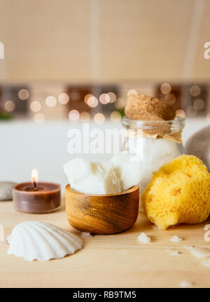 Replacing cosmetic products with natural coconut oil moisturizer cream. Solid coconut oil chunks in small wooden cup with other bath body care product Stock Photo