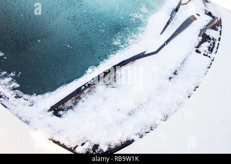 Close up view of a car windscreen wipers or windshield wipers witch are frozen and stuck in snow and ice outdoors in winter. Stock Photo
