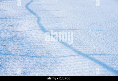 Smooth snow bluish-white surface with shadow on a striped fence Stock Photo