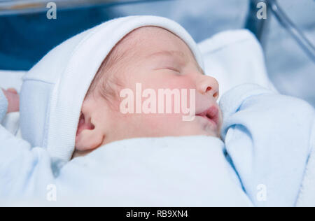 Face-up position sleeping newborn baby. Few hours-old baby at hospital crib Stock Photo