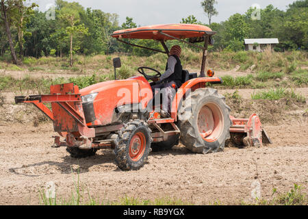 Thai farmers are using a tractor to prepare the soil for growing rice. Stock Photo
