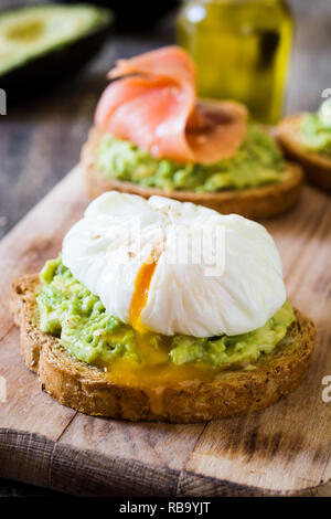 Toasted breads with poached eggs, avocado and salmon. Close up Stock Photo