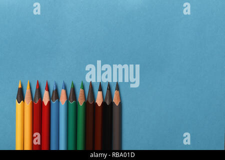 Multicolored pencils lie on blue paper background Stock Photo