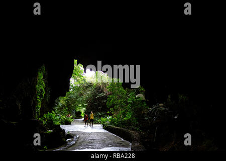 Mother and son standing under limestone cave at Ibaruma Sabichi Cave, Ishigaki, Japan