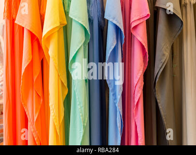 Fashion clothes on clothing rack - bright colorful closet. Close-up of rainbow color choice of trendy female wear on hangers in store closet or spring cleaning concept. Summer home wardrobe. Stock Photo