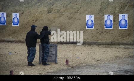 YORKTOWN, Va. (Dec. 21, 2016) Aviation Ordnanceman 1st Class Anthony Finn instructs Logistics Specialist 2nd Class Yohlanna Court through a handgun course at the Cheatham Annex Small Arms Range. The course trains Sailors assigned to the Security Department aboard USS George Washington (CVN 73) who may carry a handgun as a patrolman. George Washington is homeported in Norfolk preparing to move to Newport News, Virginia for the ship’s refueling complex overhaul (RCOH) maintenance. Stock Photo