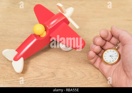 pocket watch in male hand on a wooden table by a toy plane Stock Photo