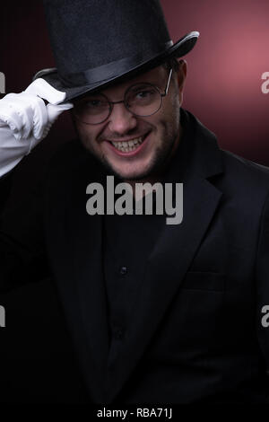 Photo of happy man in black hat in white gloves on blank red background Stock Photo