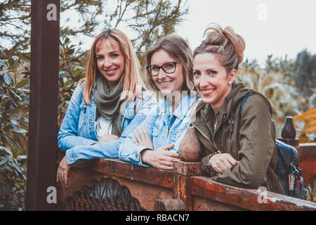 Three young women with winter clothing posing in a wooden balustrade Stock Photo